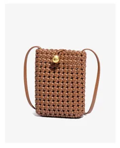 Detailed close-up view of brown woven leather phone bag featuring chic gold sphere clasp.