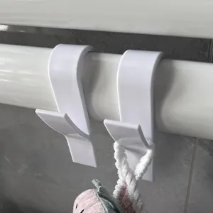 Detail van witte kunststof radiator handdoekhaken, handig badkamer ophangrek voor stangen.