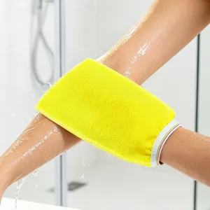 Primer plano detallado de un guante de baño exfoliante amarillo vivo en uso con agua en la ducha.