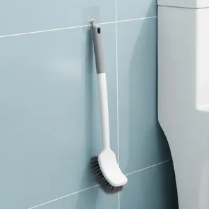 Detailansicht der grau-weißen, wandmontierten, gebogenen Toilettenbürste im Badezimmer.