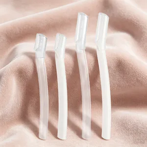 Detailed close-up view of white eyebrow razors with protective covers on pink fabric.