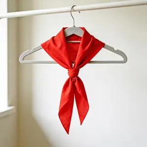Détail de foulard triangulaire rouge, matière en coton doux, nœud proprement noué sur cintre.