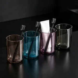 Detailed shot of transparent plastic toothbrush cups in 4 colors, modern minimalist bathroom set.