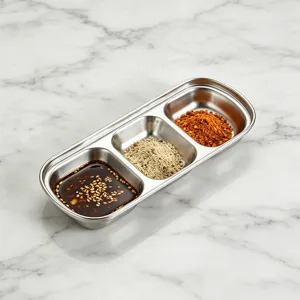 Detailed shot of a 3-compartment stainless steel dipping sauce dish on marble.