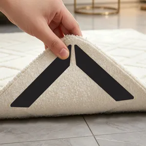 Detail view of black triangular carpet anti-slip stickers installed under a soft fluffy rug.