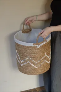 Panier à linge en jonc de mer fait main avec doublure en lin blanc et poignées robustes.