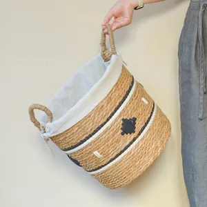 Panier à linge tressé en paille fait main avec doublure en tissu pour le rangement à maison.