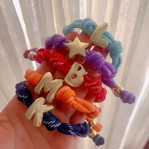 Colorful braided rope bracelets with shiny gold letter charms, perfect for DIY handmade jewelry.