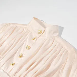 Detailopname van de Franse blouse met hoge hals en geplooide parelknopen voor stijl.