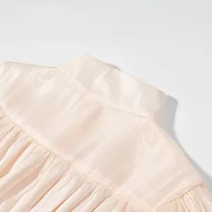 Close-up detail van de elegante geplooide opstaande kraag en het gelaagde juk op de jurk.
