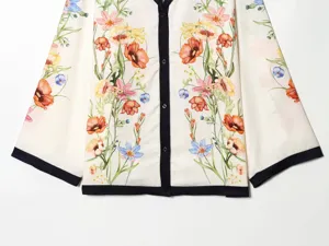 White vintage floral print blouse detail, featuring contrast black button placket.