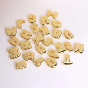 Closeup of glossy gold 3D bubble letter charms, smooth surface DIY jewelry pendant details.