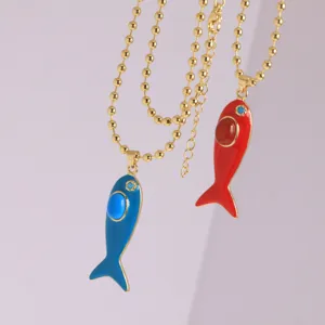 Detail view of the 18K gold plated enamel fish pendant necklace with sparkling zircon stones.