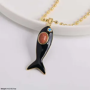Gold-tone beaded chain necklace featuring an enamel black fish pendant with shimmering stone.