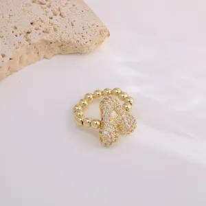Detailed close-up of gold-plated copper micro-paved cubic zirconia alphabet ring design.