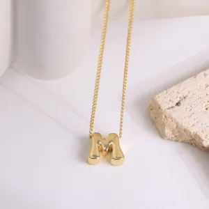 Vue détaillée d'un collier pendentif lettre M en or, avec chaîne délicate et finition brillante.