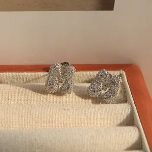 Close-up detail of sparkling zircon pavé alphabet letter stud earrings in wooden jewelry box