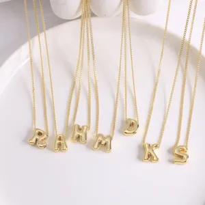 Vue détaillée du pendentif lettre doré, cuivre 18K lisse, collier ras de cou élégant.