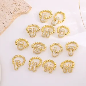 Detailed view of fashion copper micro-paved cubic zirconia alphabet letter rings in gold finish.