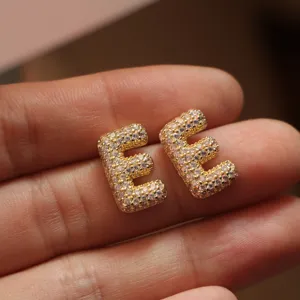 Detail shot of elegant gold letter E stud earrings, micro-paved with sparkling zircon stones.