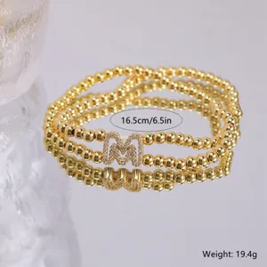 Gold plated zircon letter M beaded stretch bracelet detail view, elegant 16.5cm size shiny jewelry.
