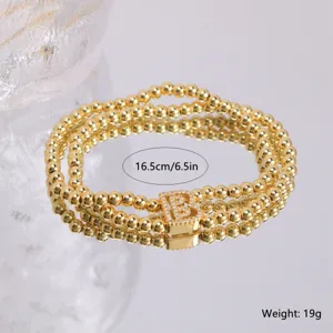 Close-up of 18k gold plated multi-strand beaded bracelet with sparkly zircon letter B charm.