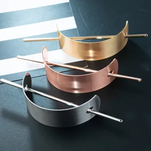 Metal hair fork detail view, showcasing the brushed texture and elegant crescent design.