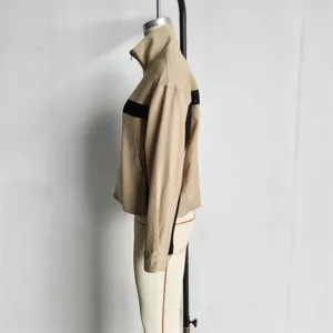 Detail view of womens high collar colorblock zip jacket in beige with black stripes.