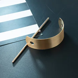Detail shot of minimalist brushed gold U-shaped metal hair stick and pin, sleek modern accessory.