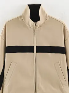 Close-up view of a women's beige stand-up collar zipper jacket featuring a bold black stripe.