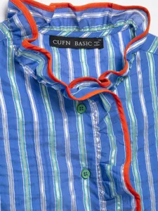 Close-up detail of women's blue striped blouse featuring an orange ruffle collar and buttons.