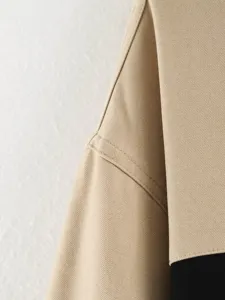 Close-up detail of women's jacket shoulder seam showing fine twill fabric and contrast color.