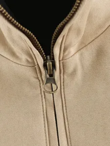 Close-up view of a casual khaki canvas jacket zipper, featuring a durable metal pull and collar.