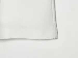 Nahaufnahme des Saumdetails von weißen Leinen Shorts mit sauberer Nahtstruktur und Stoff.