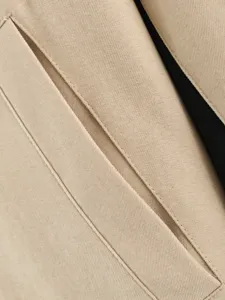 Detailed view of women's beige twill jacket pocket with black contrast lining, fine stitching.