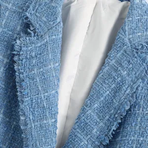 Close up view of light blue tweed blazer jacket showing textured fabric and fringe edge.