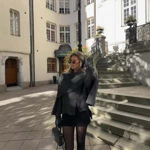 Detail view of the dark grey asymmetrical wrap knit coat styled with elegant accessories.