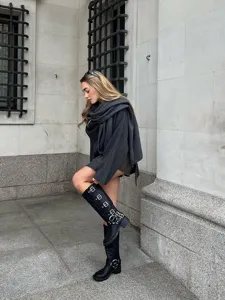 Detail view of asymmetric grey knit scarf coat in urban street scene, stylish autumn outfit.