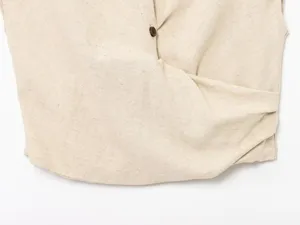 Detail view of a beige linen cropped top with button closure and stylish wrapped design.