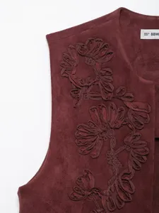 Close-up of dark red suede vest with intricate 3D floral embroidery detail and collar label.