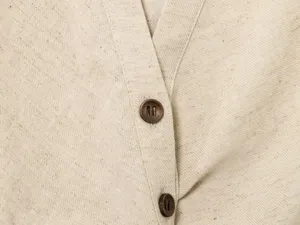 Linen blend fabric detail shot featuring two buttons on neutral beige material close up