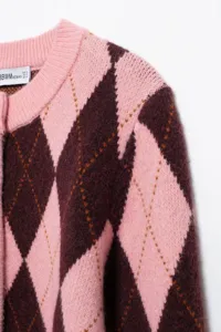 Gedetailleerde close-up van een roze en bruine ruitjes gebreide cardigan met fijne kraag.