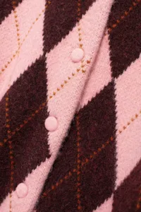 Close-up detail van gebreid vest met roze en bordeauxrode argyle patroon en knopen.
