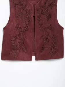Close-up detail of burgundy faux suede vest featuring exquisite floral vine embroidery.