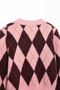 Detailopname van een roze en bruine damestrui met argyle patroon en een ronde halslijn.