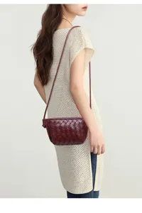Nahaufnahme Detail der burgunderroten geflochtenen Leder Umhängetasche am eleganten Model.