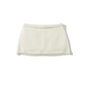 Detailed close-up view of the white knitted mini skirt featuring a stylish scalloped hem design.
