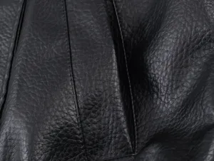 Black leather jacket fabric detail, premium litchi grain texture and neat stitching close-up.