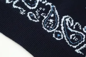 Detailed shot of dark blue knit cardigan featuring white and light blue paisley pattern.