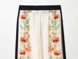 Close-up detail of cream casual trousers with elegant floral print and black side stripes.
